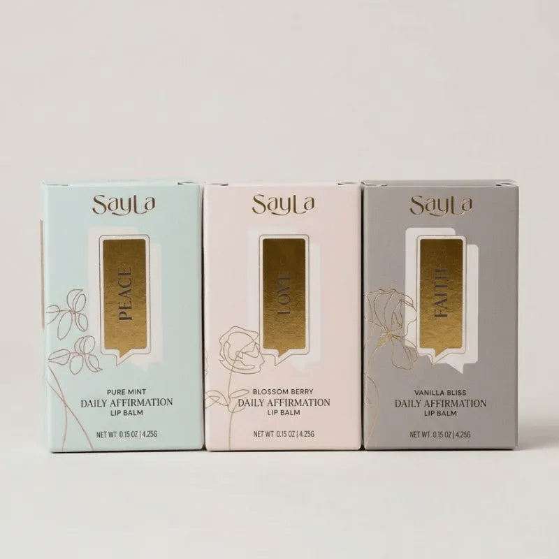 Three Sayla lip balm boxes in different colors on a light background